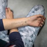 Eine junge Frau mit einem selbst gestochenen Tattoo im Unterarm