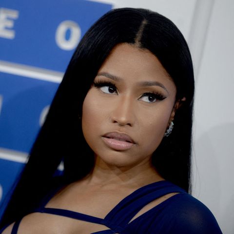 Nicki Minaj steht vor einer Wand und fasst diese mit einer Hand an, sie schaut dabei zur Seite