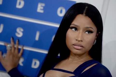 Nicki Minaj steht vor einer Wand und fasst diese mit einer Hand an, sie schaut dabei zur Seite