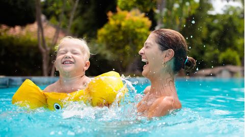 Schwimmhilfen für Kinder: Kleiner Junge mit Schwimmflügeln und seiner Mutter im Pool