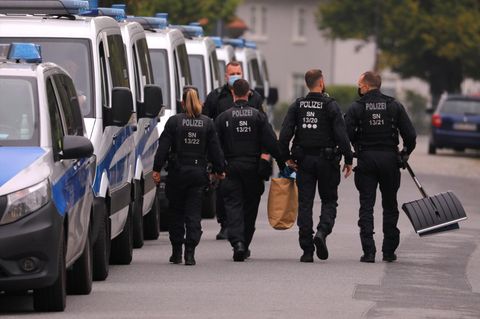 Bereitschaftspolizisten gehen neben ihren Fahrzeugen.