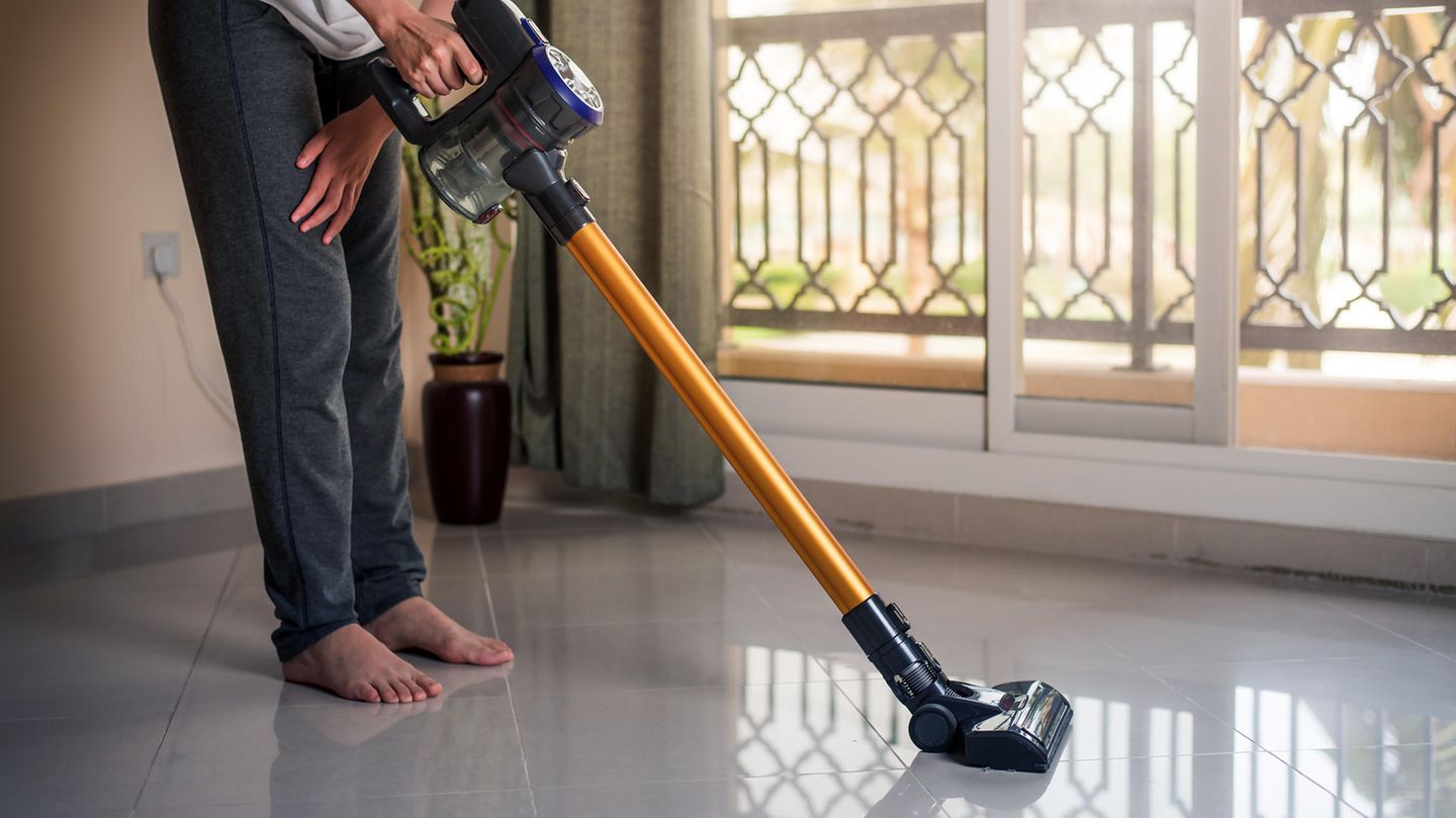 Dyson V10 Absolute: Ein Mann saugt mit seinem Akku-Sauger den Boden.
