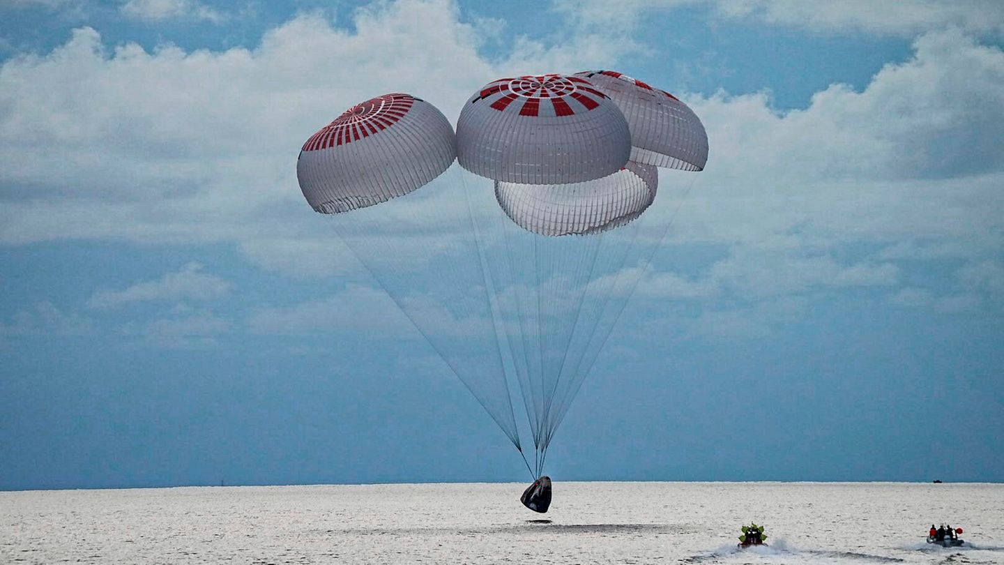 In diesem Bild aus einem SpaceX-Video gleitet eine SpaceX-Kapsel mit vier Personen an Bord vor der Küste Floridas mit Fallschirmen in den Atlantik.
