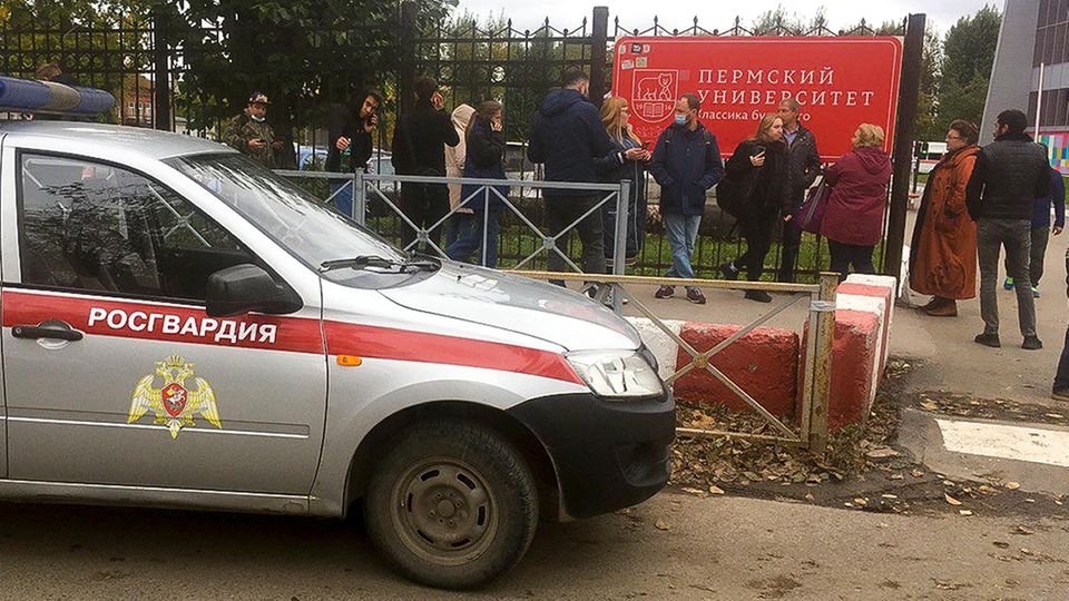 Perm Ein silber-rotes Polizeiauto steht vor einem Metallzaun mit einem roten Schild mit kyrillischer Schrift darauf