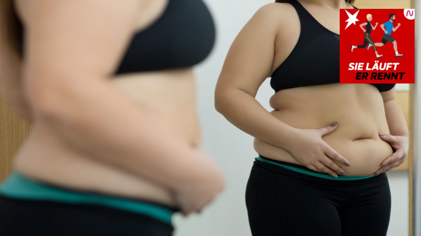 Eine Frau betrachtet ihren Bauch im Spiegel