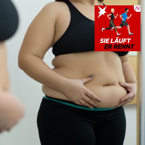 Eine Frau betrachtet ihren Bauch im Spiegel