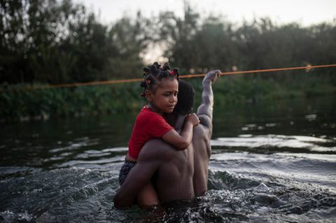 Ein Vater überquert mit seiner Tochter den Rio Grande