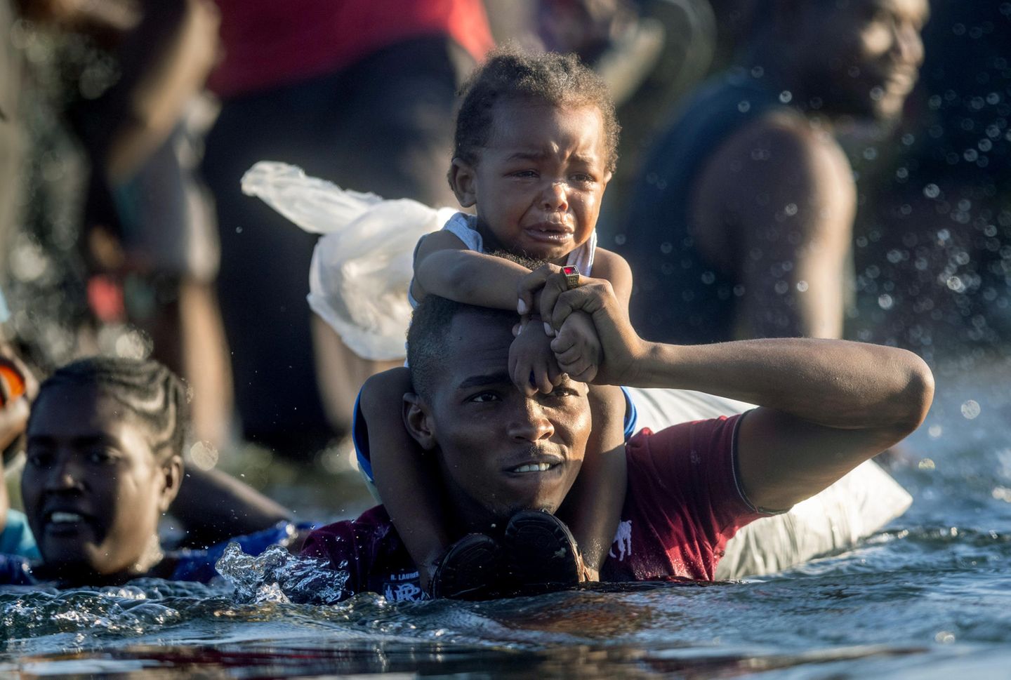 Mit einem Kleinkind auf den Schultern durchquert dieser haitianische Flüchtlinge den Rio Grande in Richtung Mexiko