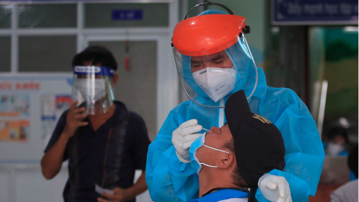 Ein Mitarbeiter im vietnamesischen Gesundheitswesen entnimmt einem Mann einen Abstrich