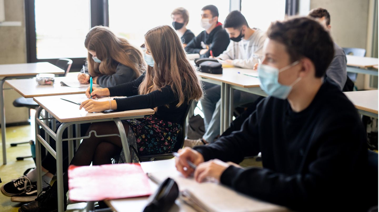Schüler und Schülerinnen im Präsenzunterricht an Tischen in einem Klassenzimmer