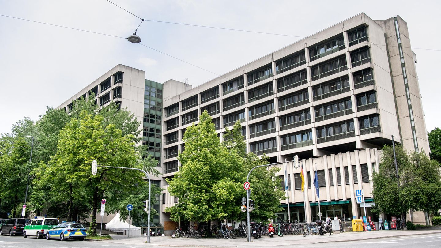 Hinter einer mehrspurigen Kreuzung steht ein mehrstöckiges betongraues Gebäude