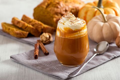 Ein Pumpkin Spice Latte neben Kürbissen und Kuchen