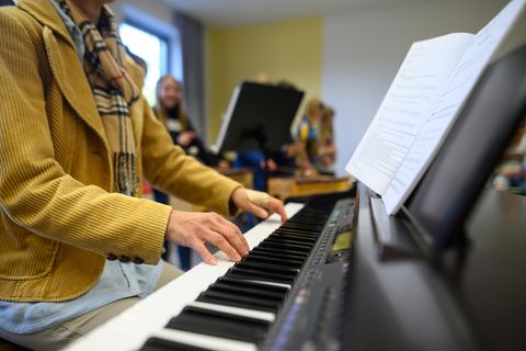 Eine Frau spielt auf einem Klavier, vor ihr steht ein aufgeschlagenes Notenheft