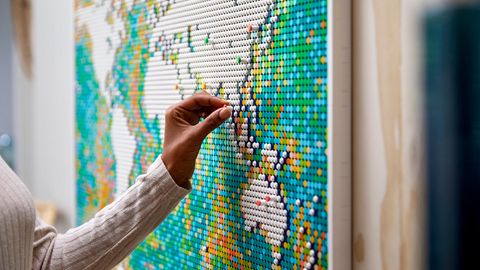 Lego Art World Map zum Hammerpreis: Frau steckt einen Pin an die Lego-Weltkarte
