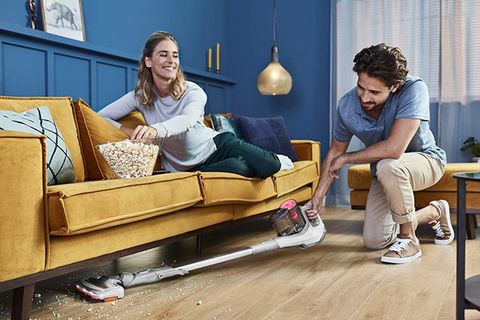 Philips SpeedPro Akku-Staubsauger: Mann saugt Krümel unter einem Sofa auf