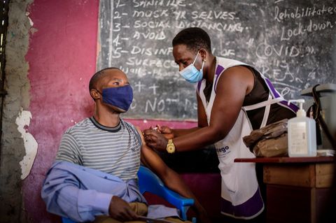 Uganda: Eine Krankenschwester verabreicht einem jungen Mann eine Impfung gegen das Coronavirus