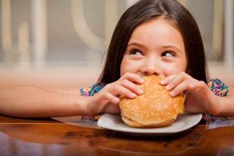 Ein Mädchen beißt in einen Burger