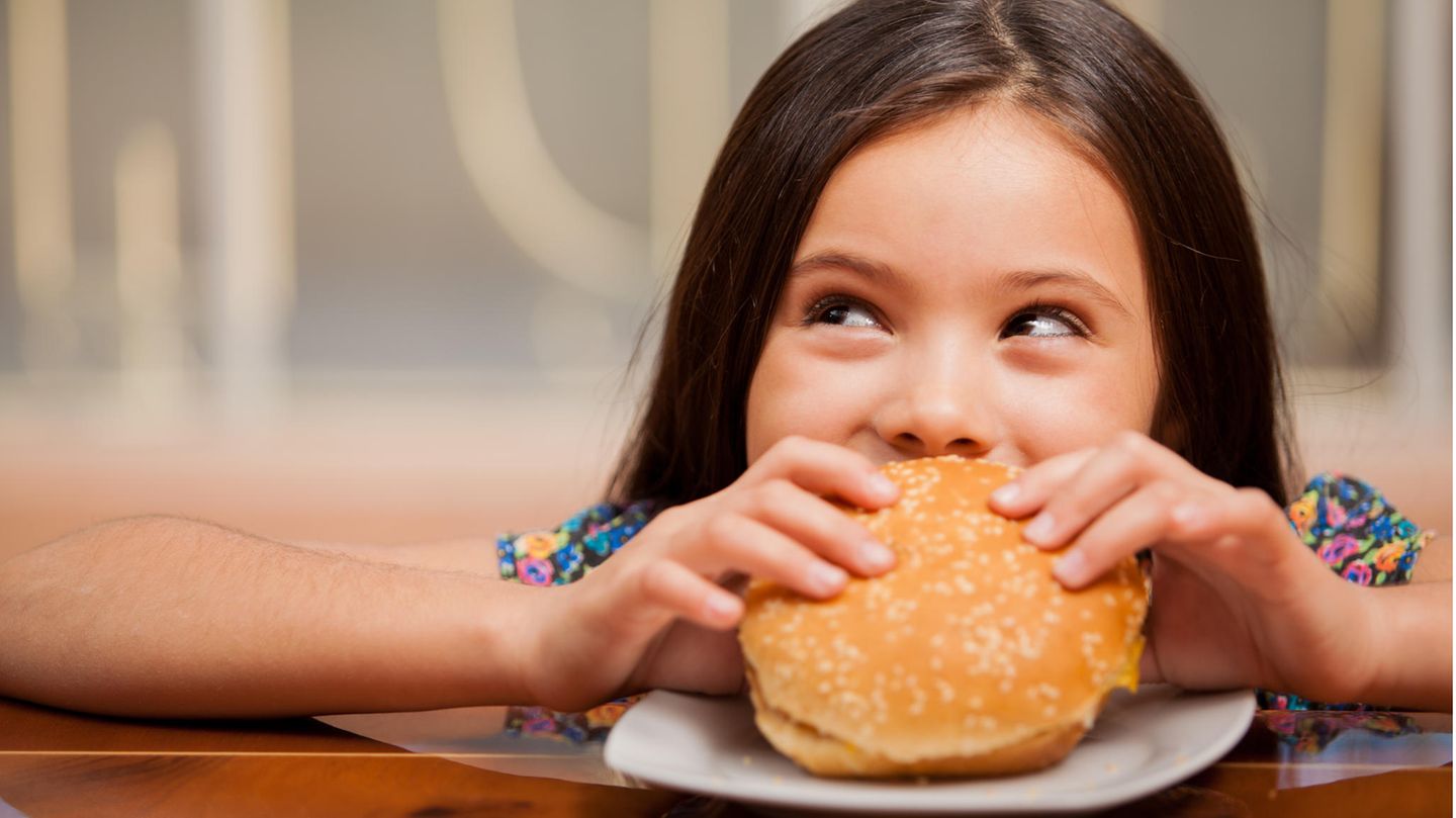Ein Mädchen beißt in einen Burger