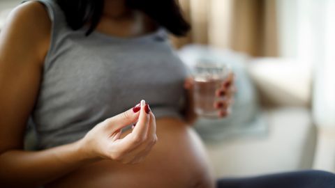 Eine Schwangere Frau nimmt eine Tablette