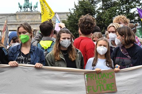 Junge Frauen und Männer halten ein weißes Stoffbanner, dessen Beschriftung allerdings nicht zu lesen ust