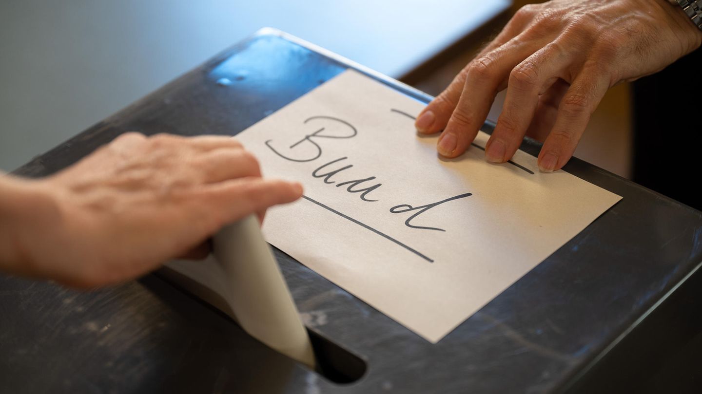 Während eine Hand einen Wahlzettel in eine Wahlurne steckt, zieht eine andere einen Zettel mit "Bund"-Aufschrift vom Schlitz Während eine Hand einen Wahlzettel in eine Wahlurne steckt, zieht eine andere einen Zettel mit "Bund"-Aufschrift vom Schlitz