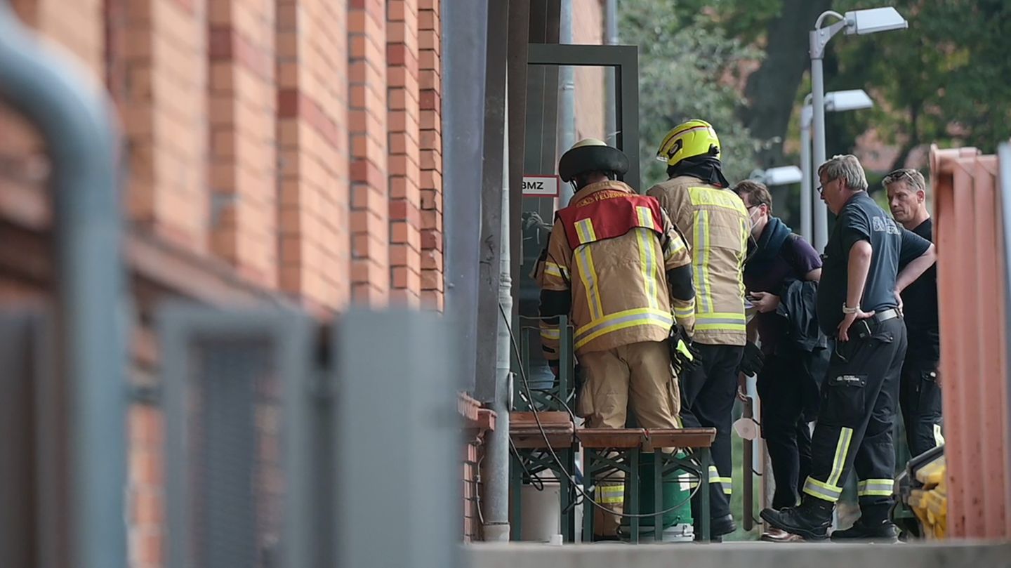 Feuerwehrleute machen sich an der Tür eines rötlichen Backstein-Gebäudes zu schaffen Feuerwehrleute machen sich an der Tür eines rötlichen Backstein-Gebäudes zu schaffen
