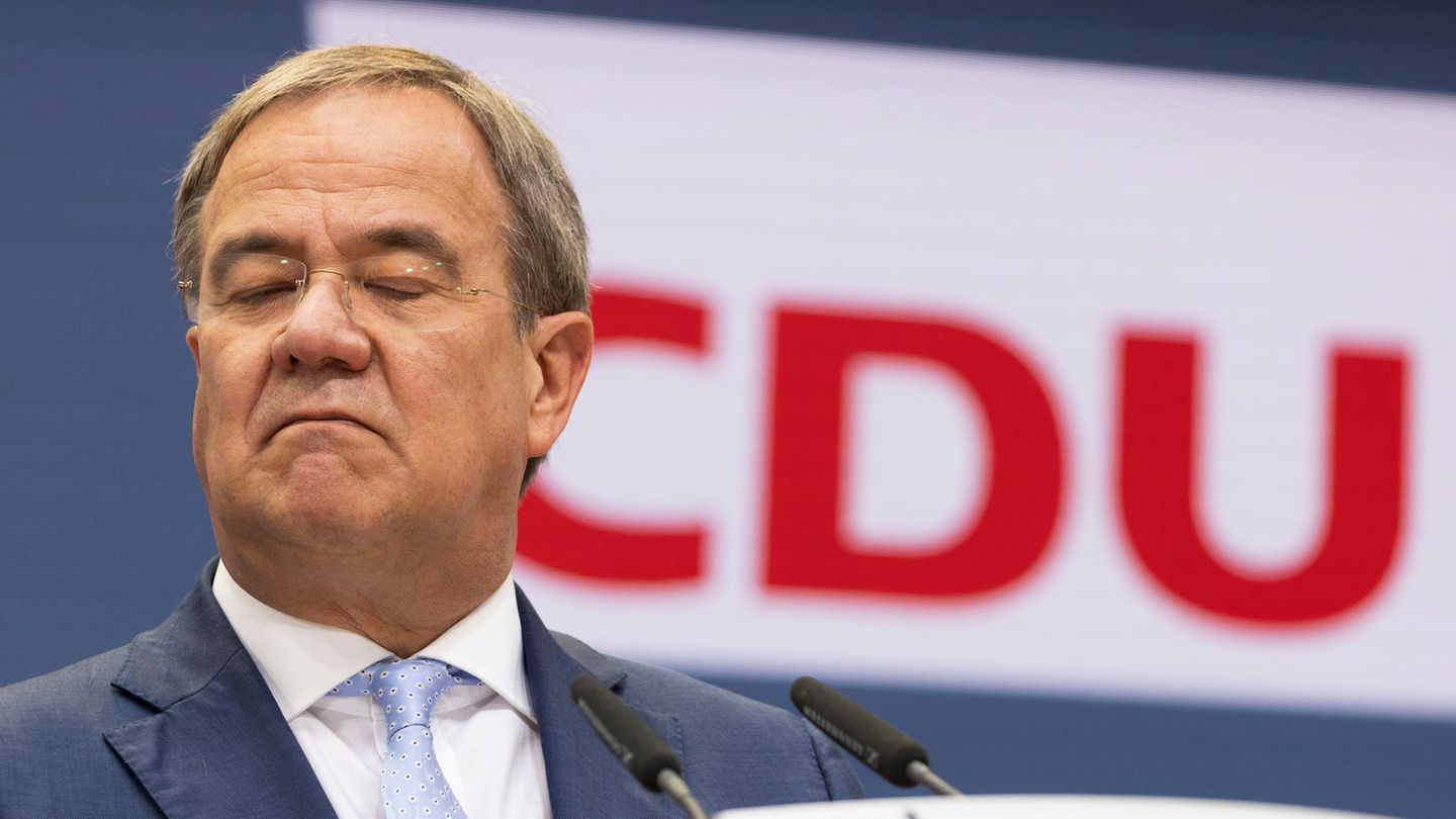 Armin Laschet mit geschlossenen Augen vor Logo