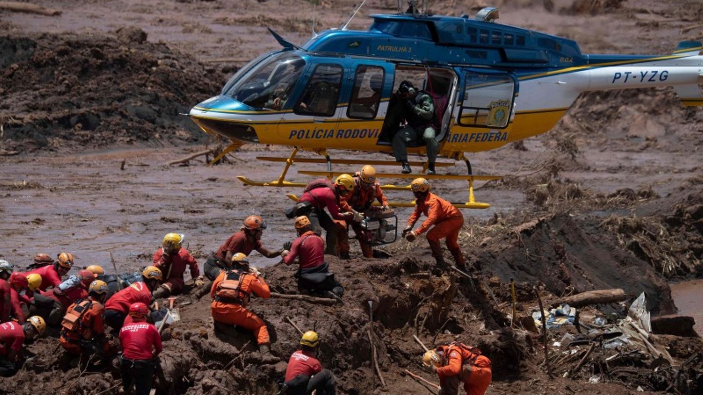 Feuerwehrleute und ein Helikopter bei der Dammbruch-Katastrophe in Brumadinho