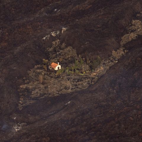 Ein Haus steht inmitten von Asche und Lava wie auf einer Insel