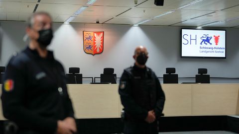 Justizbeamte mit Mundschutz stehen in Itzehoe in einem leeren Gerichtssaal