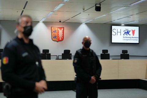 Justizbeamte mit Mundschutz stehen in Itzehoe in einem leeren Gerichtssaal