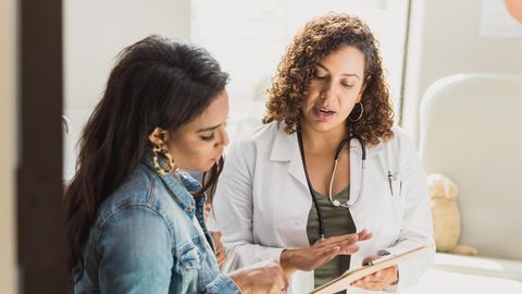 Symbolbild Gendermedizin: Eine Ärztin zeigt einer Frau etwas auf einem Blatt