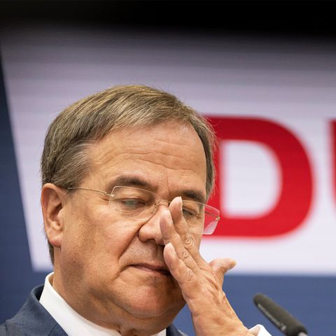 Ein älterer weißer Mann im Anzug und mit randloser Brille wischt sich mit der linken Hand übers Gesicht