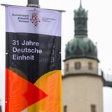Plakat "31 Jahre Deutsche Einheit" vor den Türmen der Kirche "Unser Lieben Frau" in Halle an der Saale. In der Stadt in Sachsen-Anhalt finden in diesem Jahr die zentralen Feiern statt. 