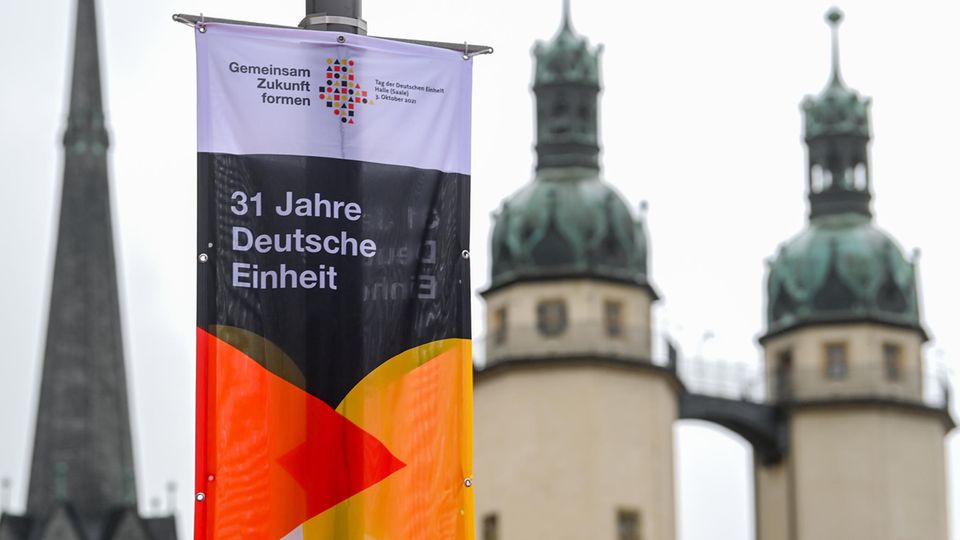 Plakat "31 Jahre Deutsche Einheit" vor den Türmen der Kirche "Unser Lieben Frau" in Halle an der Saale. In der Stadt in Sachsen-Anhalt finden in diesem Jahr die zentralen Feiern statt. 