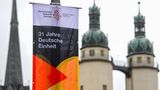 Plakat "31 Jahre Deutsche Einheit" vor den Türmen der Kirche "Unser Lieben Frau" in Halle an der Saale. In der Stadt in Sachsen-Anhalt finden in diesem Jahr die zentralen Feiern statt. 