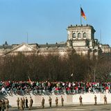 Das Berliner Reichstagsgebäude – damals noch ohne gläserne Kuppel – und die "besetzte" Mauer in den historischen Tagen im November 1989. Der Reichstag ist längst Sitz des Bundestages geworden, der sich in diesen Tagen nach der Wahl am 26. September neu konstituiert.