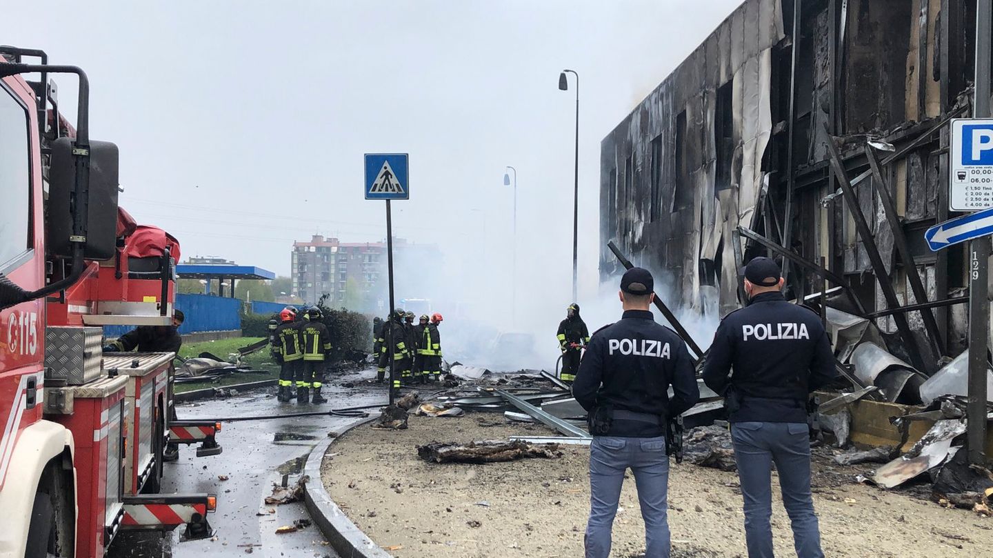 Feuerwehrleute und Polizisten stehen an der Absturzstelle eines Flugzeugs in San Donato, einem Vorort von Mailand