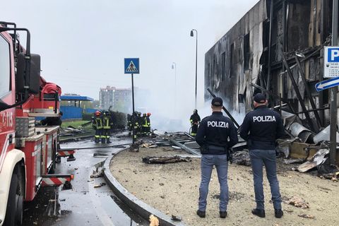Feuerwehrleute und Polizisten stehen an der Absturzstelle eines Flugzeugs in San Donato, einem Vorort von Mailand