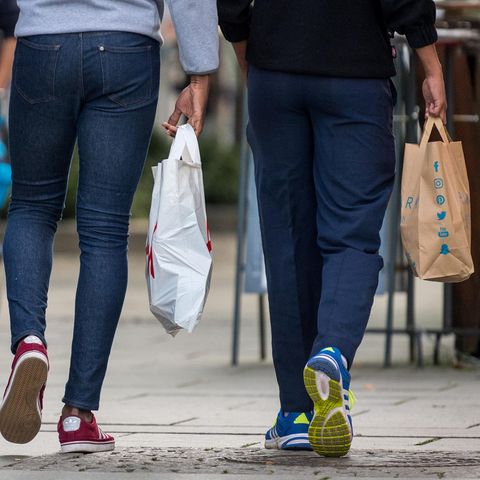 Drei Junge Männer mit Einkaufstaschen flanieren über eine Einkaufsmeile