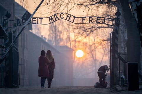 Besucher stehen vor dem Eingangstor von Auschwitz-Birkenau