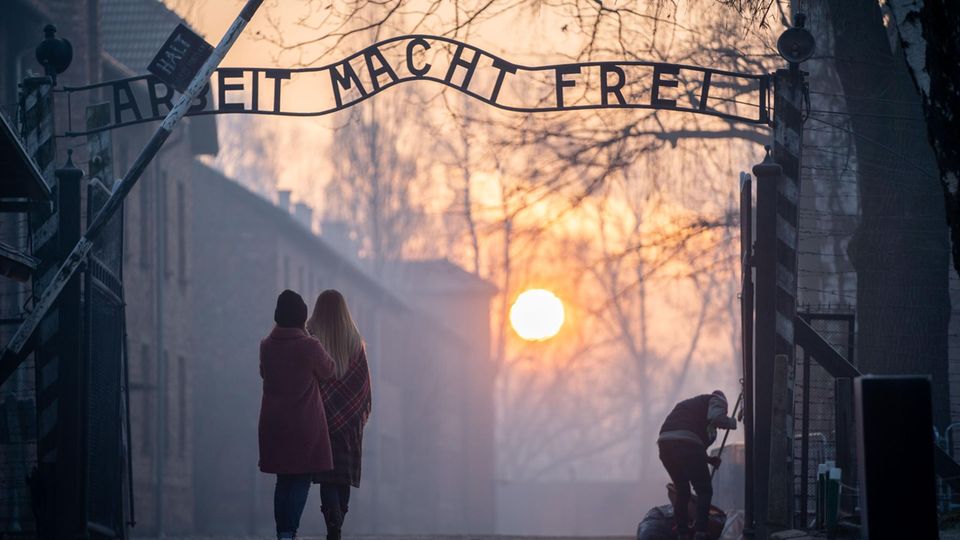 Besucher stehen vor dem Eingangstor von Auschwitz-Birkenau