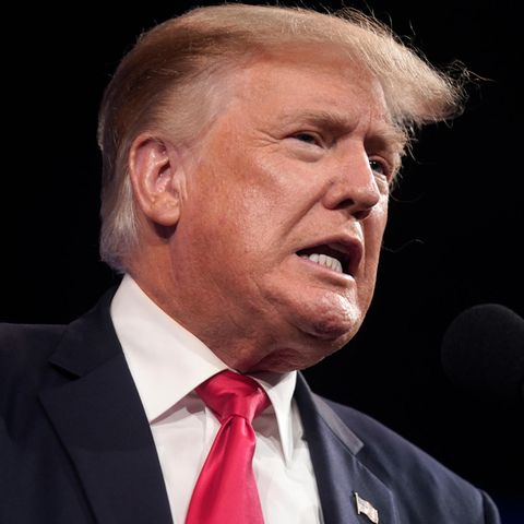 Donald Trump mit verzerrtem Mund vor einem Mikrofon