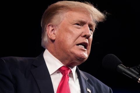 Donald Trump mit verzerrtem Mund vor einem Mikrofon
