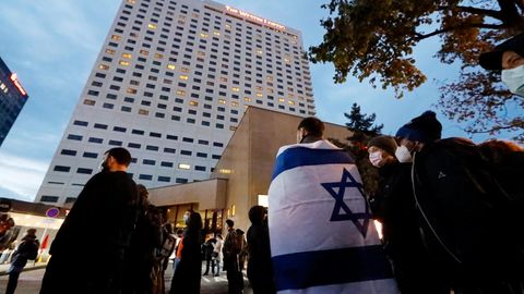 Menschen versammeln sich vor dem Westin Hotel in Leipzig, einer trägt eine Israel-Flagge