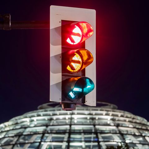 Eine Ampel vor der Kuppel des Reichstagsgebäudes leuchtet in einer Langzeitbelichtung in allen drei Phasen