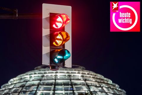 Eine Ampel vor der Kuppel des Reichstagsgebäudes leuchtet in einer Langzeitbelichtung in allen drei Phasen