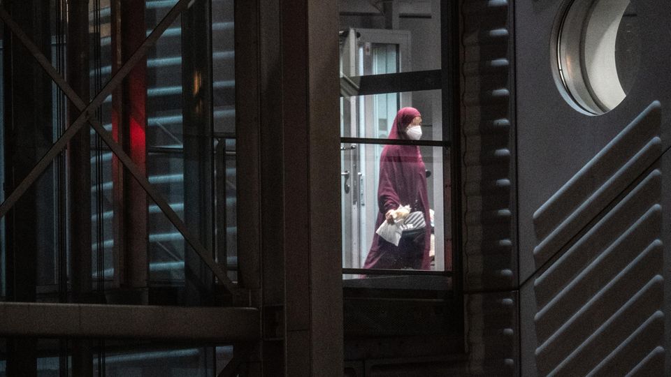 Eine verschleierte Frau mit einer Maske verlässt den Gangway einer Chartermaschine.