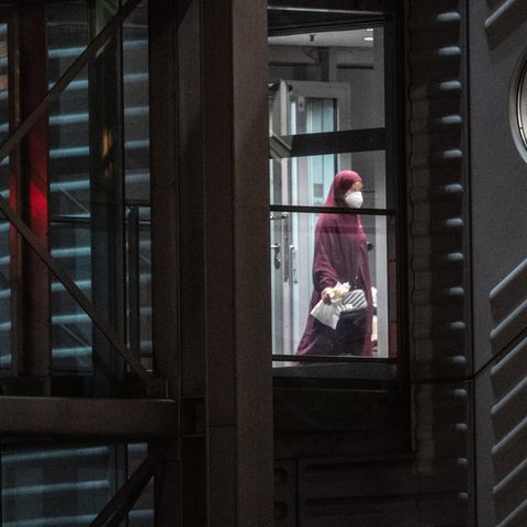 Eine verschleierte Frau mit einer Maske verlässt den Gangway einer Chartermaschine.