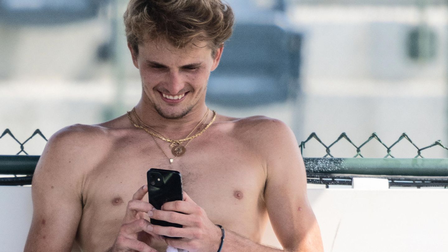 Tennisprofi Alexander Zverev sitzt nach dem Training beim Turnier in Indian Wells auf einer Bank und schaut auf sein Handy.